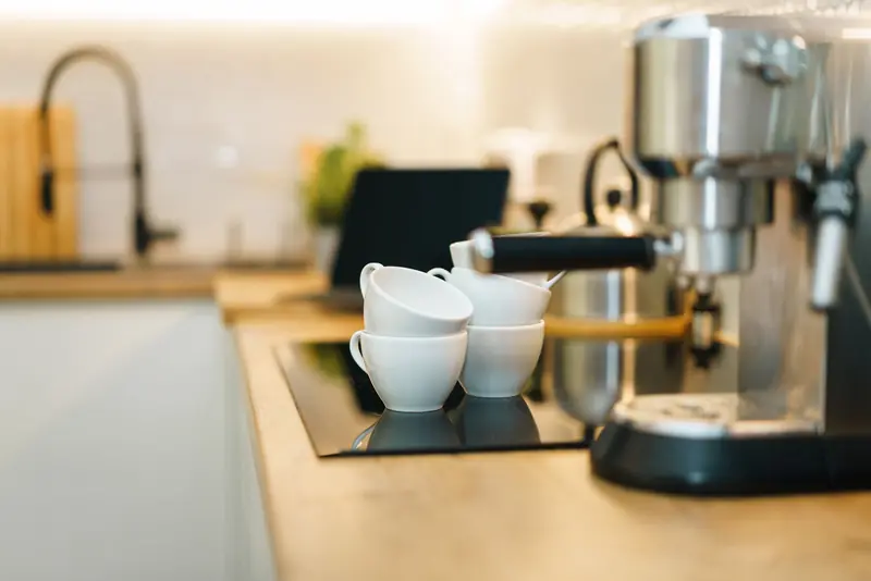 A modern espresso machine with coffee cups on a kitchen counter, showcasing a cozy and inviting setup