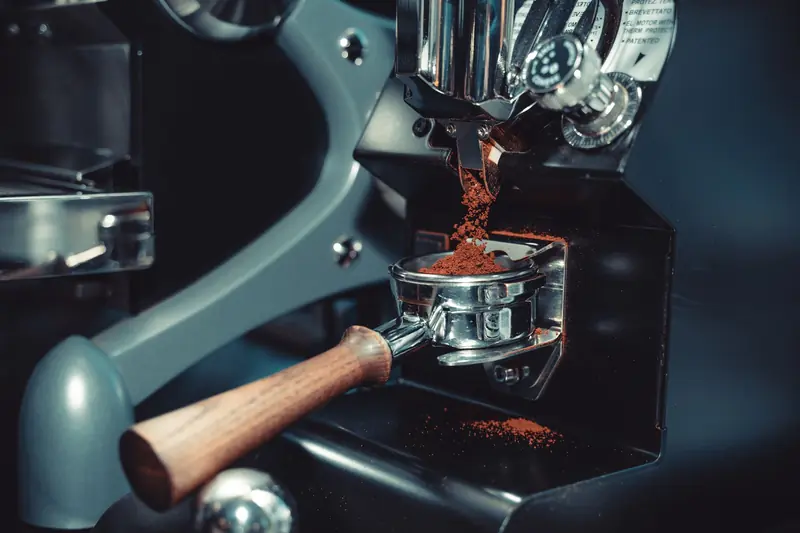 Close-up of a coffee machine portafilter collecting freshly ground coffee