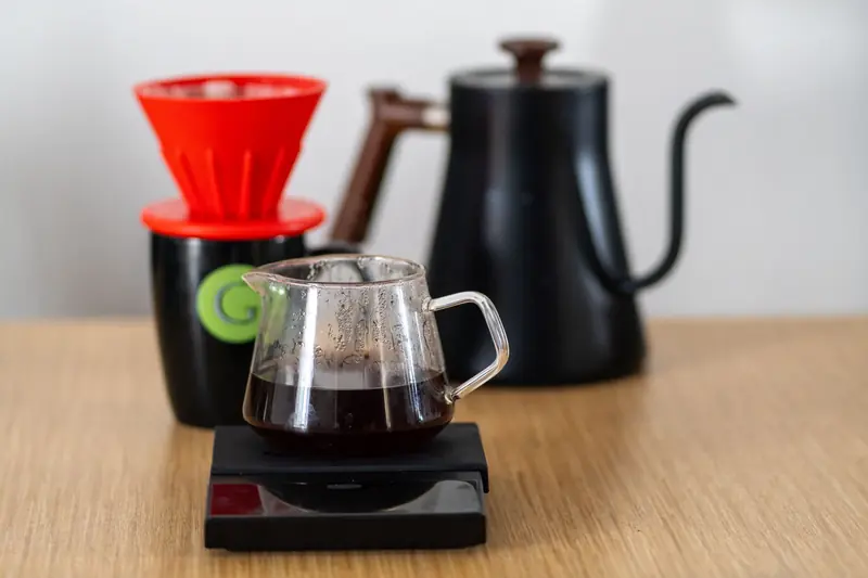 Close-up of a V60 coffee setup with dripper, scale, and kettle, highlighting specialty coffee brewing