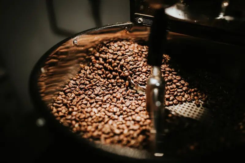 Close-up of freshly roasted coffee beans in a large industrial coffee roaster, showcasing rich textures and warm tones