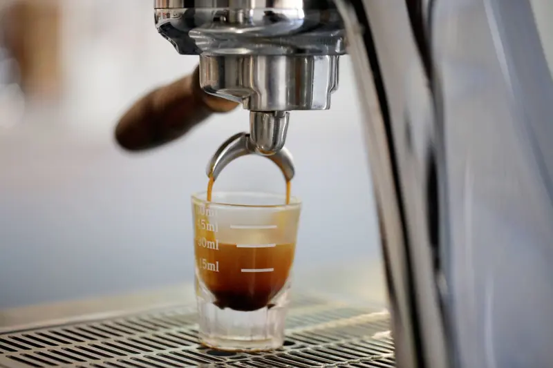 A close-up view of an espresso shot being brewed from a coffee machine into a glass cup