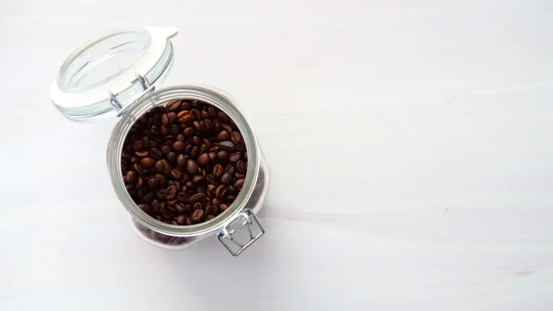 Top view of a glass jar filled with aromatic roasted coffee beans