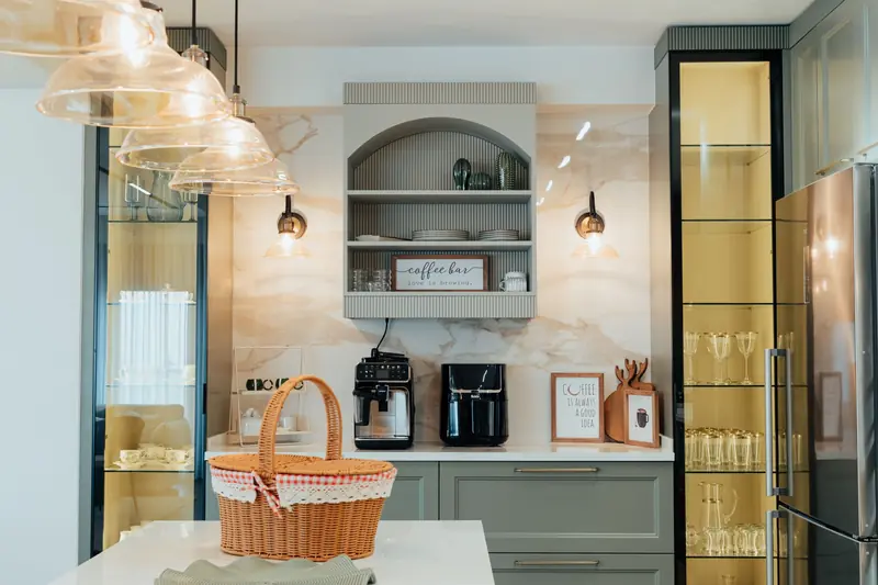 Elegant modern kitchen featuring a coffee bar, glass cabinets, and stylish lighting for a warm ambiance