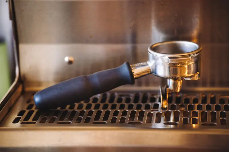 Close-up of a portafilter resting on an espresso machine, ideal for coffee enthusiasts