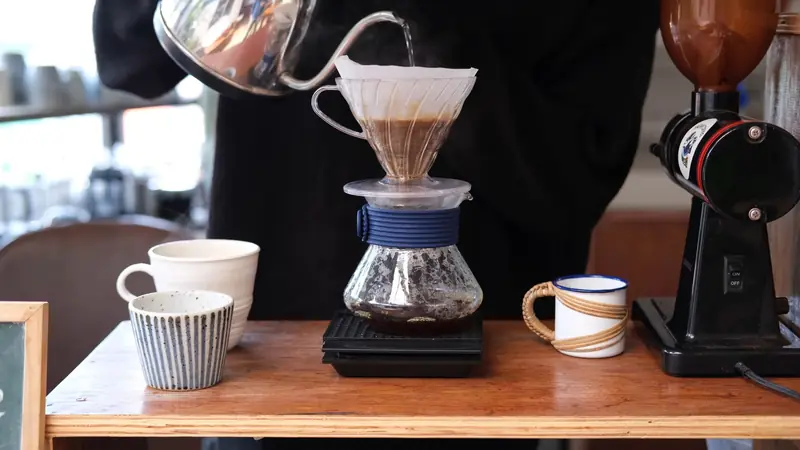 Close-up of a pour over coffee brewing process with cups and grinder